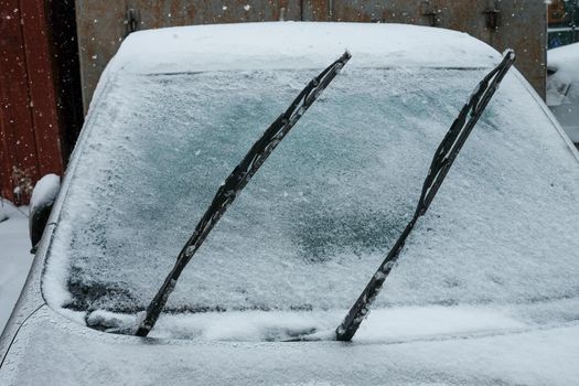 the raised wiper on the car is covered with ice and snow. Ice covered car window close up.