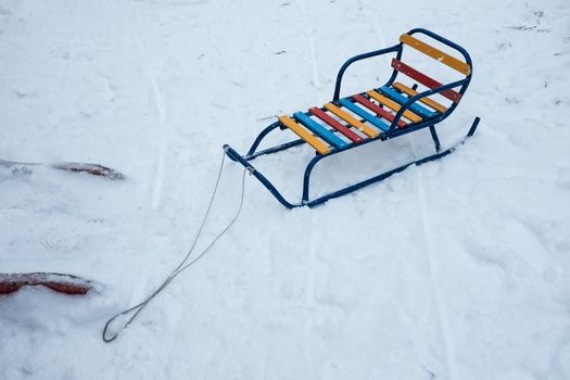 color wood and metal children sledges on the white snow.