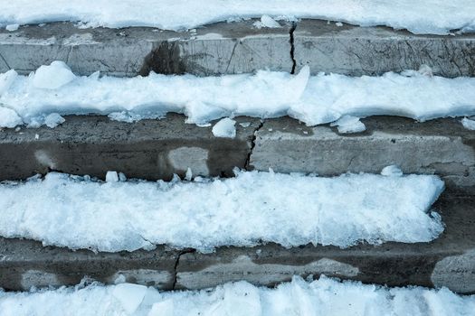 partly snow covered concrete stairs in urban environment.