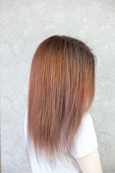 A girl with long, straight and beautiful brown hair. Hair care at home.