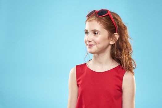 girl with curly hair sunglasses red dress and childhood fun blue background. High quality photo
