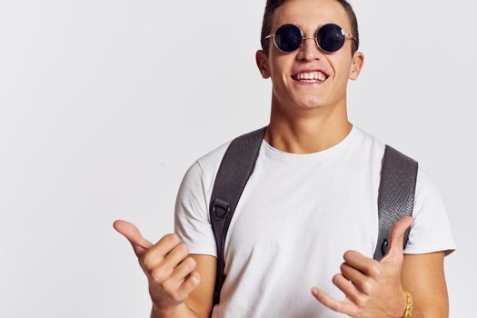 handsome man with backpack on his back gesturing with his hands in a t-shirt and wearing glasses Copy Space portrait cropped view