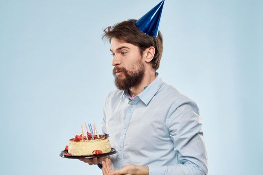 A man in a shirt with a cake in his hands and a festive cap on his head. High quality photo