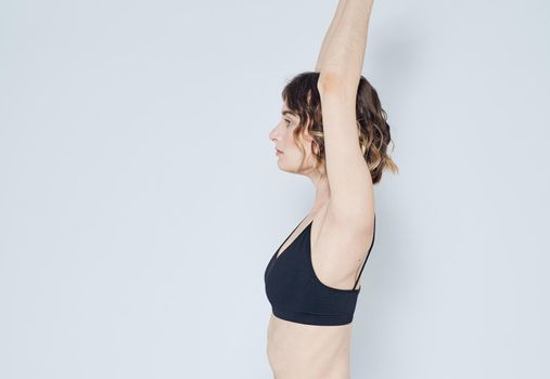 A sportive woman is doing exercises on a light background gesturing with her hands. High quality photo