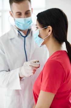 a patient being examined by a doctor wearing a medical mask, protective gloves and a stethoscope around her neck. High quality photo