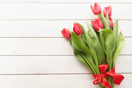 Bunch of spring tulips over white wooden background, top view flat lay