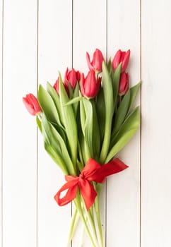 Bunch of spring tulips over white wooden background, top view flat lay