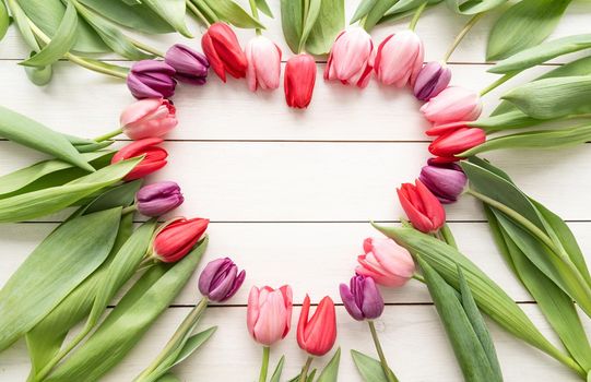 Love concept. Heart shape made of spring tulip flowers, copy space inside. Top view flat lay