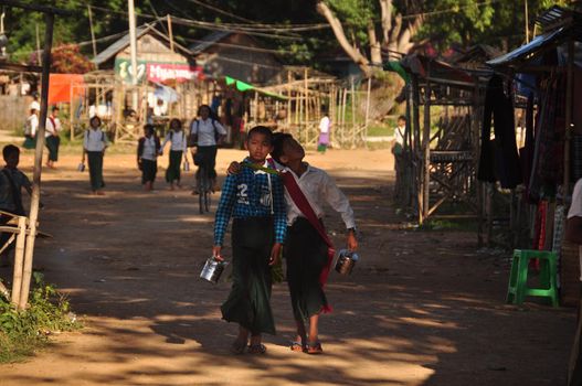INLE, MYANMAR - NOVEMBER 29, 2015: Ethnic kids after school in village, View of ethnic pupils walking in rural village after school