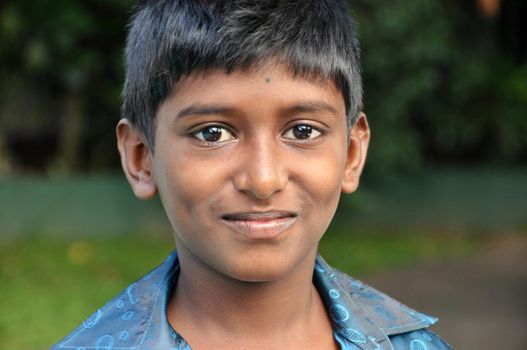 KANDY, SRI LANKA - 17th DEC, 2011: Young smiling ethnic boy looking at camera, Portrait of young smiling Indian boy in blur shirt looking at camera in nature.