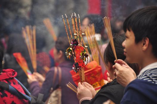 HONG KONG - 22th FEBRUARY, 2015: Crowd of people with aromatic sticks near temple, View of crowded square of people carrying burning sticks in front of Wong Tai Sin temple. Celebrating New Year.