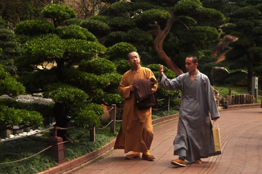 HONG KONG - 22th FEBRUARY, 2015: Monks walking in green oriental garden, View of ethnic monks in robes walking on pathway in Nan Lian garden