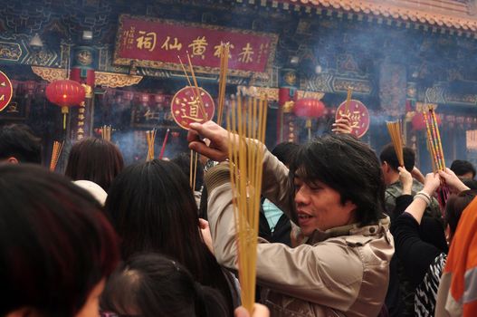 HONG KONG - 22th FEBRUARY, 2015: Crowd of people with aromatic sticks near temple, View of crowded square of people carrying burning sticks in front of Wong Tai Sin temple. Celebrating New Year.