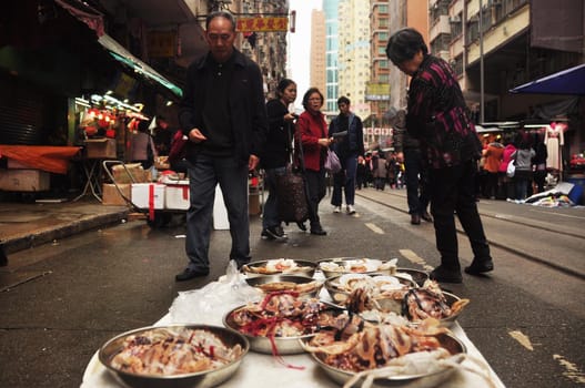 HONG KONG - 22th FEBRUARY, 2015: Local street market with people around, Marine delicatessen on stall for sale on street with people walking around. Street food asia.