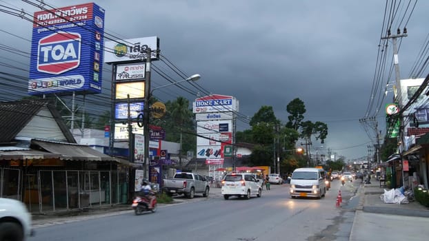 KOH SAMUI ISLAND, THAILAND - 21 JUNE 2019 Busy transport populated city street in cloudy day. Typical street full of motorcycles and cars. Thick blue clouds before storm during wet season