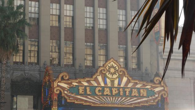 LOS ANGELES, CALIFORNIA, USA - 7 NOV 2019: El Capitan Theater shiny entrance sign. Retro signboard glowing on Walk of Fame, Hollywood boulevard. Illuminated cinema industry vintage symbol in LA city.