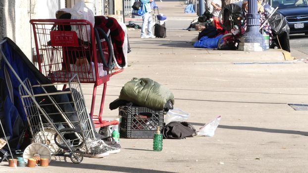 SAN DIEGO, CALIFORNIA USA - 4 JAN 2020: Stuff of homeless street people on walkway, truck on roadside. Begging problem in downtown of city near Los Angeles. Jobless beggars live on pavements.