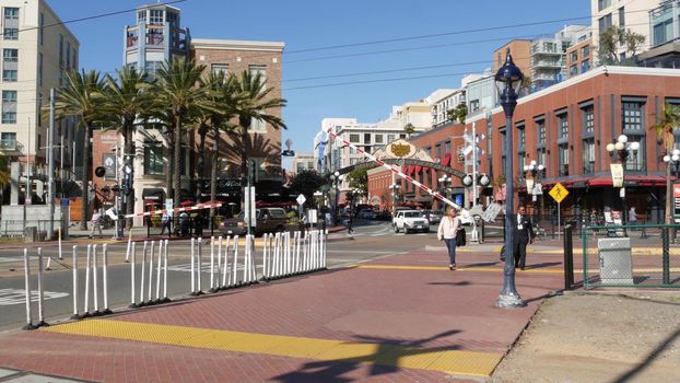 SAN DIEGO, CALIFORNIA USA - 13 FEB 2020: Gaslamp Quarter historic entrance arch sign. Retro signboard on 5th ave. Iconic vintage signage. Trolley track level crossing, people on road intersection.