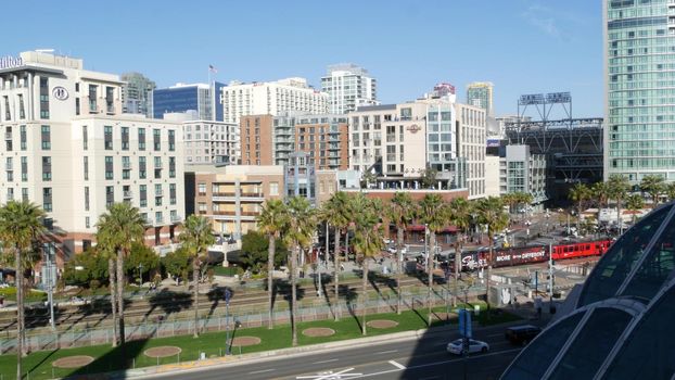 SAN DIEGO, CALIFORNIA USA - 13 FEB 2020: MTS red trolley and metropolis urban skyline, highrise skyscrapers in city downtown. From above aerial view, various buildings in Gaslamp Quarter and tram.