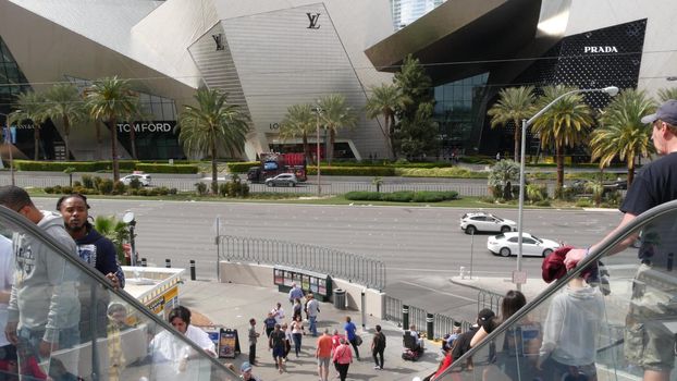 LAS VEGAS, NEVADA USA - 7 MAR 2020: Futuristic CityCenter luxury urban skyline. Contemporary metropolis skyscrapers and Crystals shopping mall. Multiracial pedestrians, interracial people on escalator