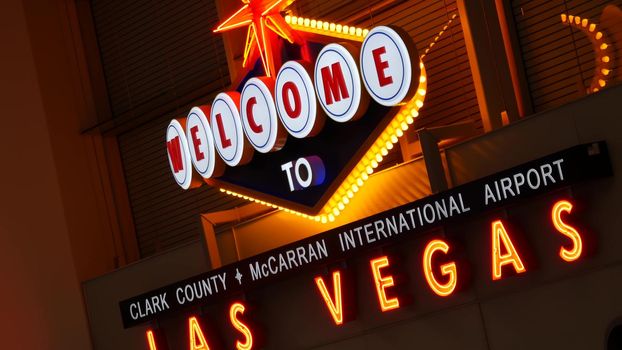 LAS VEGAS, NEVADA USA - 9 MAR 2020: Welcome to fabulous Sin City illuminated retro neon sign inside McCarran airport. Iconic greeting vintage styled signboard glowing. Gambling casino resort symbol.
