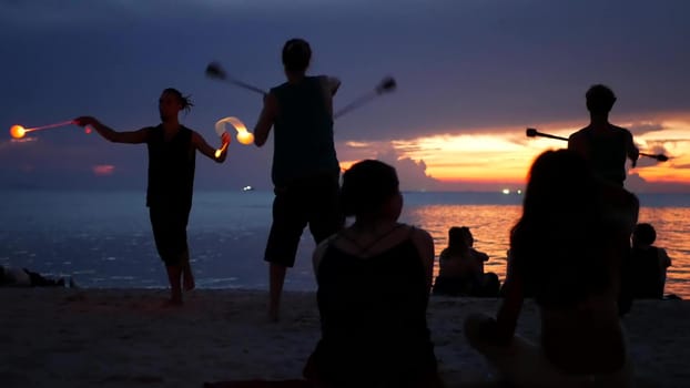 PHANGAN, THAILAND - 23 MARCH 2019 Zen Beach. Silhouettes of performers on beach during sunset. Silhouettes of young anonymous entertainers rehearsing on sandy beach against calm sea and sundown sky