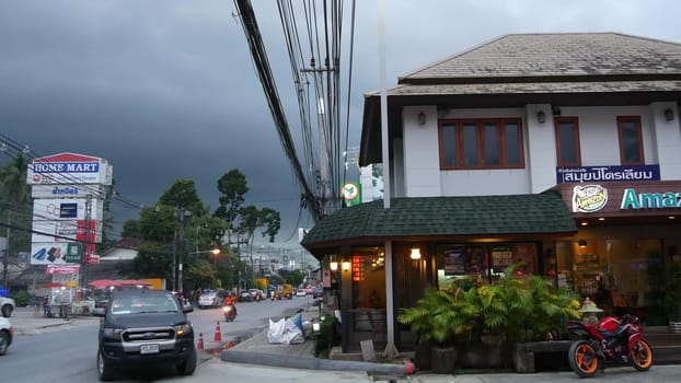 KOH SAMUI ISLAND, THAILAND - 21 JUNE 2019 Busy transport populated city street in cloudy day. Typical street full of motorcycles and cars. Thick blue clouds before storm during wet season