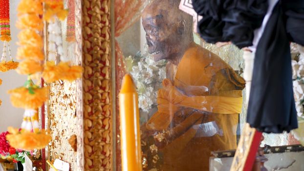 KOH SAMUI ISLAND, THAILAND - 17 JULY 2019: Wat Khiri Wongkaram Buddhist Temple. The mummified body of monk and gold leaf. Exotic tradition of storing the relics of saints who died during meditation