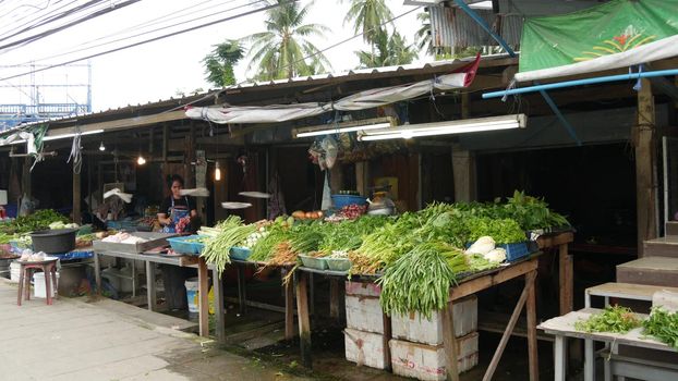 KOH SAMUI ISLAND, THAILAND - 10 JULY 2019: Food market for locals. Lively ranks with groceries. Typical daily life on the street in Asia. People go shopping for fruits vegetables, seafood and meat