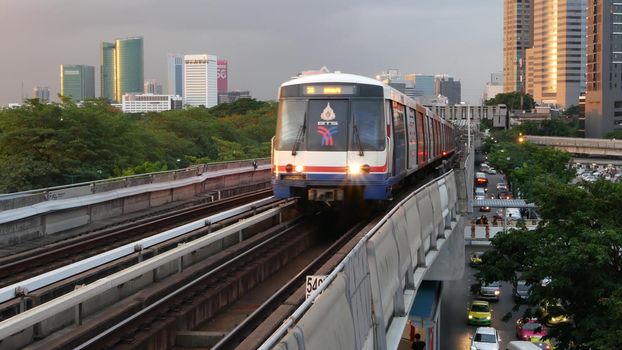 BANGKOK, THAILAND - 10 JULY, 2019: View of modern asian city from bts sky train platform. Train on metro rail road station. Public transportation in Krungtep downtown. Evening steet traffic in Asia