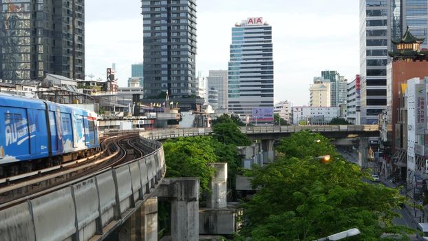 BANGKOK, THAILAND - 13 JULY, 2019: View of modern asian city from bts sky train platform. Train on metro rail road station. Public transportation in Krungtep downtown. Evening steet traffic in Asia