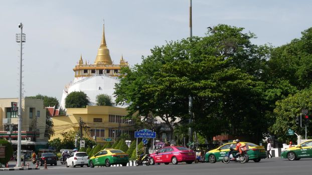 BANGKOK, THAILAND - 11 JULY, 2019: Rush hour traffic near Wat Saket in capital. Famous asian landmark and travel destination. Ancient religious monastery and public transport on the road in downtown