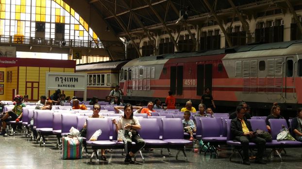 BANGKOK, THAILAND - 11 JULY, 2019: Signpost with name of city. Hua Lamphong main railroad station of state railway transport, SRT. Passengers on platform near sign board. People and trains on tracks