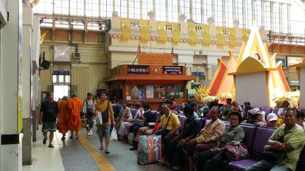 BANGKOK, THAILAND - 11 JULY 2019: Hua Lamphong railroad station, state railway transport infrastructure SRT. Buddhist holy Monk in traditional orange robe. Monks yellow religious clothes among people