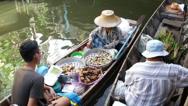 BANGKOK, THAILAND, 13 JULY 2019 Lat Mayom floating market. Traditional classic khlong river canal, local women in long-tail boat with oriental thai cusine assortment. Iconic asian street food selling