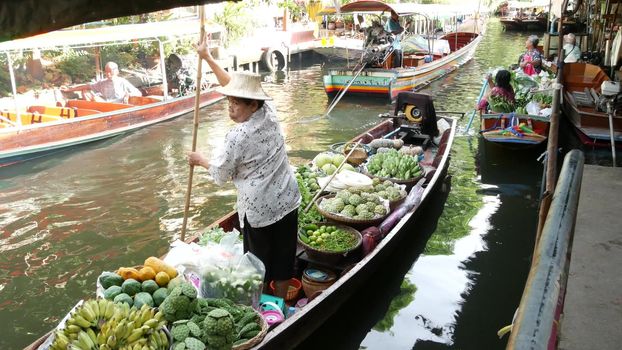 BANGKOK, THAILAND - 13 JULY 2019: Lat Mayom floating market. Traditional classic khlong river canal, local women farmers, long-tail boats with fruits and vegetables. Iconic asian street food selling