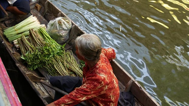 BANGKOK, THAILAND - 13 JULY 2019: Lat Mayom floating market. Traditional classic khlong river canal, local women farmers, long-tail boats with fruits and vegetables. Iconic asian street food selling