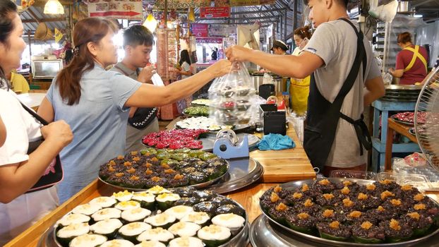 BANGKOK, THAILAND - 13 JULY 2019: Lat Mayom khlong river canal traditional classic floating market. Iconic local asian street food selling. Sellers and buyers at the counters with exotic goods.