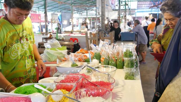 BANGKOK, THAILAND - 13 JULY 2019: Lat Mayom khlong river canal traditional classic floating market. Iconic local asian street food selling. Sellers and buyers at the counters with exotic goods.