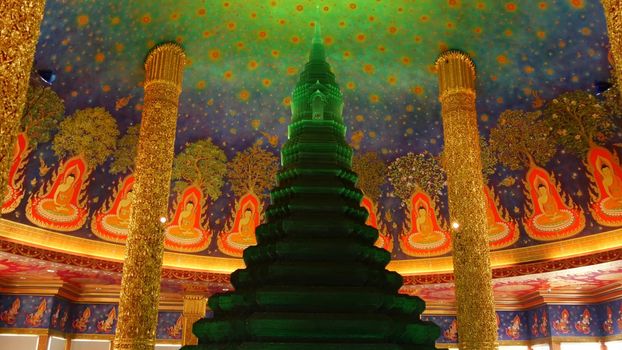 BANGKOK, THAILAND - 13 JULY, 2019: Wat Pak Nam or Paknam traditional oriental buddhist temple interior. Emerald glass stupa under vivid colorful ceiling, circular dome roof colored with acid colors.