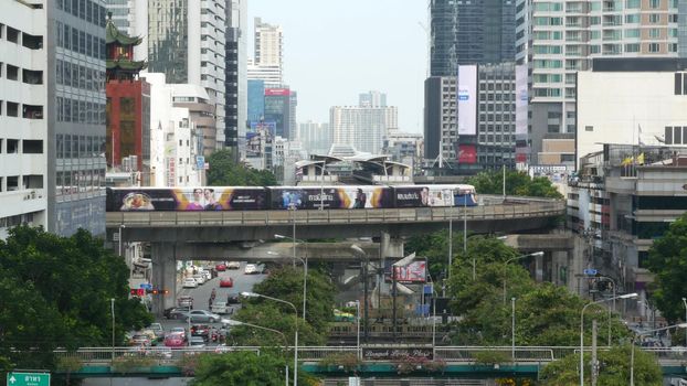 BANGKOK, THAILAND - 13 JULY, 2019: Traffic on modern city street. Contemporary train riding on railroad bridge over road with cars in center of capital