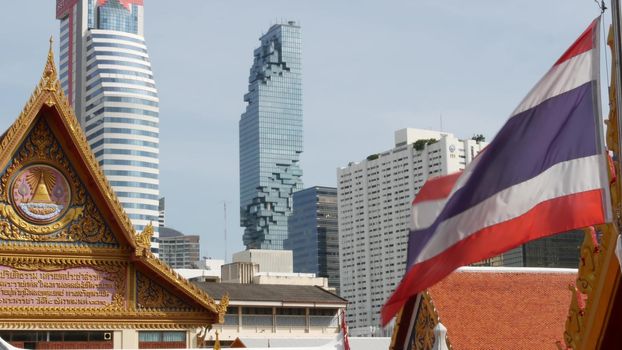 BANGKOK, THAILAND - 13 JULY, 2019: Conceptual contrast of oriental old traditional ancient temple and modern new futuristic Mahanakhon skyscraper. Classic buddhist wat compared to urban cityscape