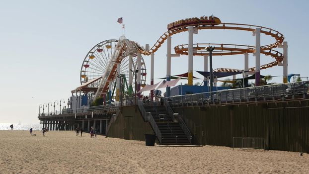 SANTA MONICA, LOS ANGELES CA USA - 28 OCT 2019: Famous classic california summertime symbol, pacific ocean beach resort. Iconic colorful retro ferris wheel and roller coaster, amusement park on pier.