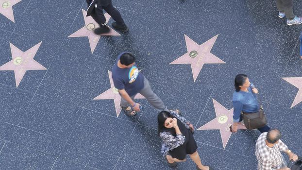 LOS ANGELES, CALIFORNIA, USA - 7 NOV 2019: Walk of fame promenade on Hollywood boulevard in LA. Pedastrians walking near celebrity stars on asphalt. Walkway floor near Dolby and TCL Chinese Theatre.