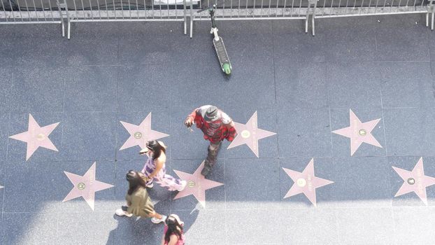 LOS ANGELES, CALIFORNIA, USA - 7 NOV 2019: Walk of fame promenade on Hollywood boulevard in LA. Pedastrians walking near celebrity stars on asphalt. Walkway floor near Dolby and TCL Chinese Theatre.