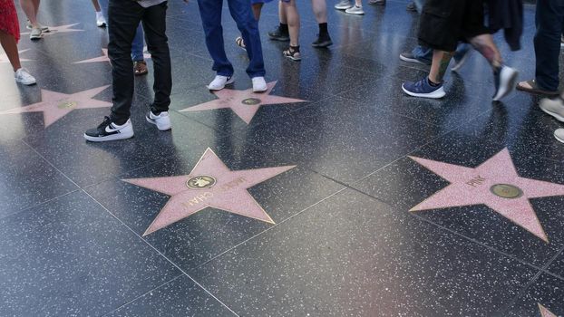 LOS ANGELES, CALIFORNIA, USA - 7 NOV 2019: Walk of fame promenade on Hollywood boulevard in LA. Pedastrians walking near celebrity stars on asphalt. Walkway floor near Dolby and TCL Chinese Theatre.