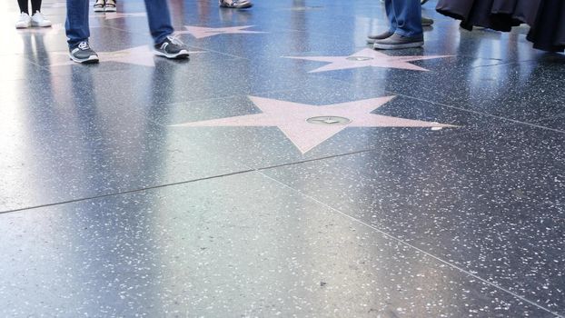 LOS ANGELES, CALIFORNIA, USA - 7 NOV 2019: Walk of fame promenade on Hollywood boulevard in LA. Pedastrians walking near celebrity stars on asphalt. Walkway floor near Dolby and TCL Chinese Theatre.