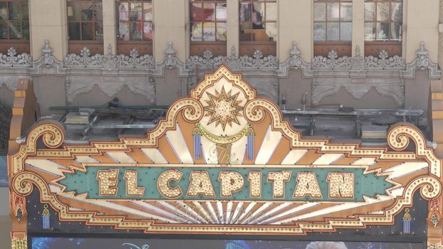 LOS ANGELES, CALIFORNIA, USA - 7 NOV 2019: El Capitan Theater shiny entrance sign. Retro signboard glowing on Walk of Fame, Hollywood boulevard. Illuminated cinema industry vintage symbol in LA city.