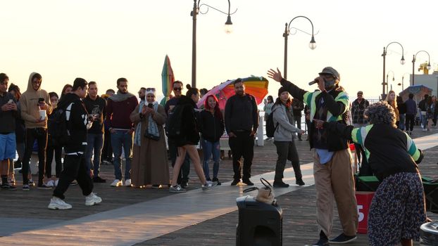 SANTA MONICA, LOS ANGELES CA USA - 19 DEC 2019: African american street performer dancing on boardwalk. Two black ethnicity positive dancers having fun. Pier promenade, smiling multiethnic pedestrians