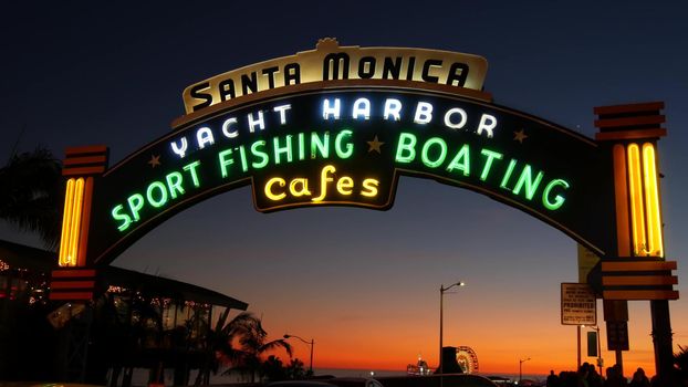 SANTA MONICA, LOS ANGELES CA USA - 19 DEC 2019: Summertime iconic vintage symbol. Classic illuminated retro sign on pier. California summertime aesthetic. Glowing lettering on old-fashioned signboard.